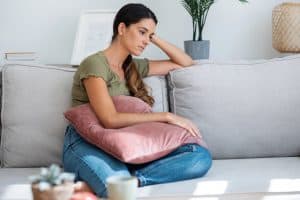 Nachdenkliche Frau auf Couch mit Kissen