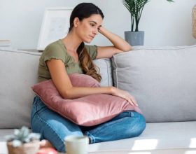 Nachdenkliche Frau auf Couch mit Kissen